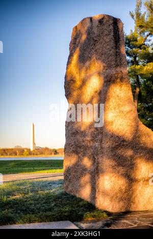 LBJ Memorial Grove Granitmonolith Washington DC | WASHINGTON, D.C., Vereinigte Staaten — Der LBJ Memorial Grove am Potomac steht als Tribut an Präsident Lyndon B. Johnson. Das 17 Hektar große Gelände verfügt über einen Granitmonolithen, umgeben von einem schlangenförmigen Muster von Wegen und Pfaden. Einheimische Bäume und Sträucher bevölkern die Landschaft und bieten Blick auf die Denkmäler der Hauptstadt auf der anderen Seite des Flusses. In dieser Aufnahme kann man das Washington Monument in der Ferne auf der anderen Seite des Potomac sehen. Stockfoto