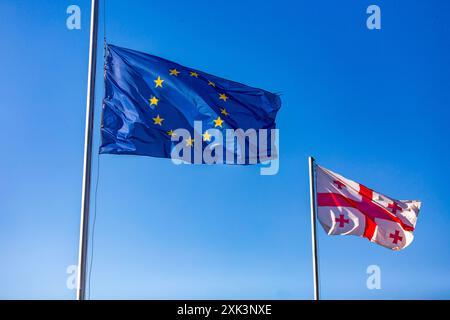 Europäische Union und georgische Flaggen winken gegen den klaren blauen Himmel in Tiflis, Georgien. Stockfoto