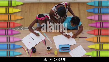 Mehrere Buntstifte gegen afroamerikanische Mutter, die ihrem Sohn bei seinen Hausaufgaben hilft Stockfoto