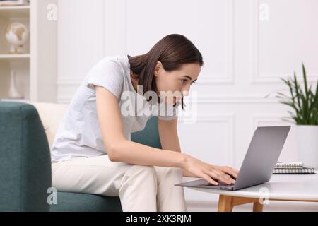 Frau mit schlechter Körperhaltung, die zu Hause einen Laptop benutzt Stockfoto