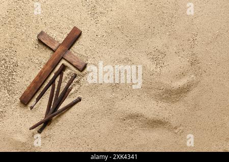 Holzkreuz mit Nägeln auf Sand. Karfreitagskonzept Stockfoto