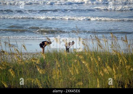 Ein junges Paar, die Hände auf den Knien ruhen, atmet am Sandstrand nach einem Morgenlauf am North Myrtle Beach, South Carolina. Stockfoto