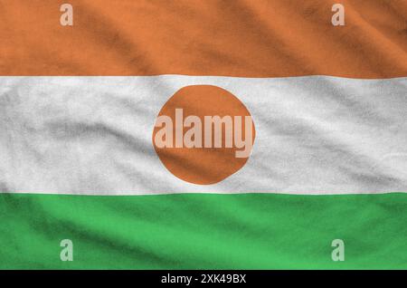 Niger-Flagge auf gefaltetem, gewelltem Stoff aus altem Tuch in Nahaufnahme dargestellt Stockfoto