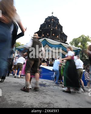 München, Deutschland. Juli 2024. Gäste tanzen im Kocherlball am Chinesischen Turm. Das traditionelle Open-Air-Volkstanz-Festival, das gewöhnlich bei Sonnenaufgang im Englischen Garten an einem Sommertag stattfindet, geht auf das 19. Jahrhundert zurück. Quelle: Felix Hörhager/dpa/Alamy Live News Stockfoto