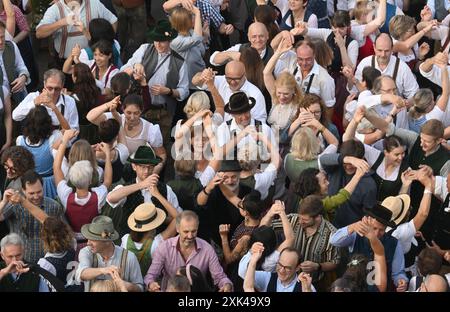 München, Deutschland. Juli 2024. Gäste tanzen im Kocherlball am Chinesischen Turm. Das traditionelle Open-Air-Volkstanz-Festival, das gewöhnlich bei Sonnenaufgang im Englischen Garten an einem Sommertag stattfindet, geht auf das 19. Jahrhundert zurück. Quelle: Felix Hörhager/dpa/Alamy Live News Stockfoto
