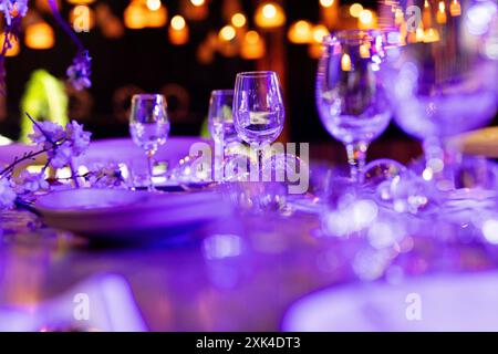 Luxuriöse Tischgedecke für feines Essen mit und Gläsern, Gießen von Wein ins Glas. Schöner unscharfer Hintergrund. Vorbereitung auf die Feiertagshochzeit. Extravagant Stockfoto