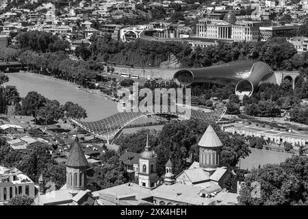 Tiflis, Georgien - 22. Juni 2024: Die Friedensbrücke ist eine bogenförmige Fußgängerbrücke, eine Stahl-Glas-Konstruktion über den Fluss Kura, die die Brücke verbindet Stockfoto