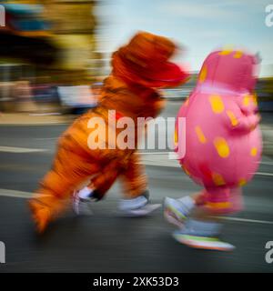 Bewegungsunschärfe des Dinosauriers und Mr. Blobby im Blackpool 10 K Fun Run entlang der Promenade Stockfoto