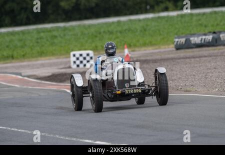 V.S.C.C. Blyton Speed Trials, Blyton Park, Blyton, Lincolnshire, England, UK. Juli 2024. Die Mitglieder des Vintage Sports Car Club (V.S.C.C.) nehmen an der fünften Runde der SpeedTrials-Meisterschaft auf dem Blyton Circuit Teil. Diese eintägige Veranstaltung mit Autos in Aktion, die bereits in den 10er Jahren und bis Ende der 30er Jahre für Sport- und Limousinenwagen hergestellt wurden und vom Austin 7, Frazer Nash, Riley bis hin zu 4,5 Liter Bentleys usw. reichen Diese Veranstaltung wird auf dem langen Kurs durchgeführt, besteht aus kurzen Geraden, schnellen und langsamen Kurven und einer atemberaubenden Haarnadelkurve, die die Fähigkeiten des Fahrers bis ans Limit unter Beweis stellt. Credi Stockfoto