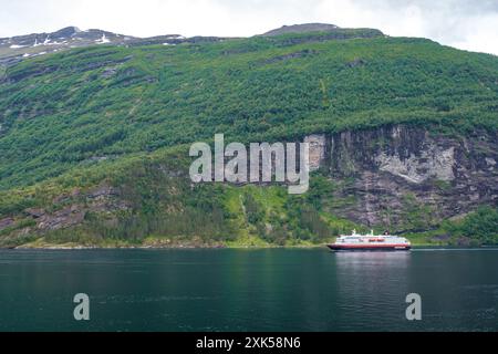 Geiranger Fjord Norwegen am 5. Juli 2024 fährt Ein großes Kreuzfahrtschiff durch einen majestätischen norwegischen Fjord, umgeben von hohen grünen Bergen und einem klaren blauen Himmel. Stockfoto