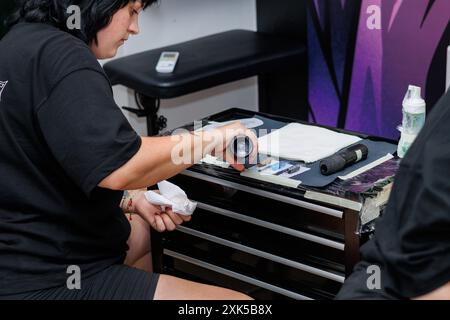 Professioneller Tätowierer, der die Werkzeuge und Utensilien überprüft, die für den nächsten Job in der Tätowierstube notwendig sind Stockfoto