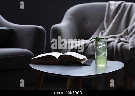 Buchen, trinken und Sessel in schwach beleuchtetem Raum Stockfoto