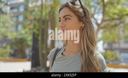 Eine junge blonde Frau genießt einen sonnigen Tag im Freien in einem grünen Stadtpark, der eine ungezwungene und ruhige Atmosphäre erzeugt. Stockfoto