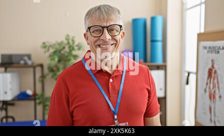 Lächelnder reifer Mann mit Brille, der ein Schlüsselband in einer Reha-Klinik trägt. Stockfoto