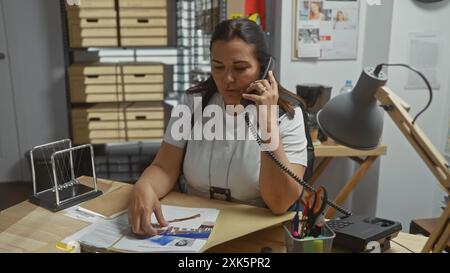 Eine fokussierte Detektivin analysiert Beweise in einem Büro, in Ordnern, einem Telefonanruf und Ermittlungsdokumenten. Stockfoto