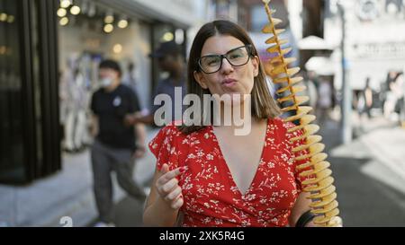 Wunderschöne hispanische Frau, die fröhlich knusprige, leckere Chips auf einem Stock in der takeshita Street, tokio isst - Reisende Junk Food Liebhaber, Sportbrille Stockfoto