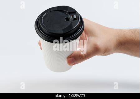 Weißer Papierbecher mit schwarzem Deckel in der Hand perspektivische Ansicht isoliert Stockfoto