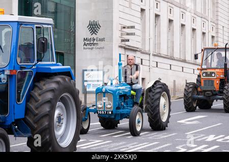 Ballymena, Nordirland - 19. Juli 2024: Vintage Tractor Rally, Retro Blue Fordson Dexta fährt vorbei am Rathaus. Stockfoto