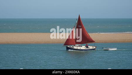 Vintage-Yacht mit rotem Segel, die in die Flussmündung des Deben bei Felixstowe Ferry eindringt. Stockfoto