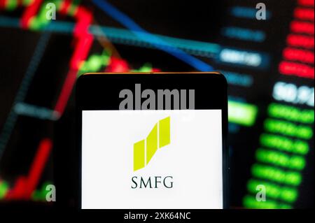 In dieser Fotoabbildung ist das Logo des japanischen multinationalen Banken- und Finanzunternehmens Sumitomo Mitsui Financial Group (SMFG) auf einem Smartphone mit einem Index-Diagramm der wirtschaftlichen Börsen im Hintergrund zu sehen. Stockfoto