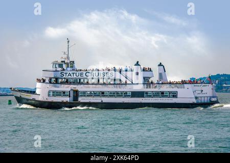 Statue of Liberty V - eines der Kreuzfahrtschiffe, die Touristen zu Liberty & Ellis Islands im Hafen von New York, USA, bringen. Stockfoto