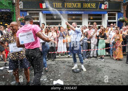 London, 21. Juli 2024. Dutzende Teilnehmer des Soho Kellner' Race laufen in Soho mit einem Tablett, Gläsern und Champagner auf einer festgelegten Strecke, um dann das Rennen zu feiern und auf den Straßen von Soho zu feiern. Bei der traditionellen Veranstaltung treten jedes Jahr Servicemitarbeiter aus vielen Bars, Pubs und Restaurants der Gegend an. Quelle: Imageplotter/Alamy Live News Stockfoto