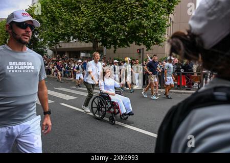 Die libanesische Fotojournalistin Christina Assi trägt die olympische Fackel, um Journalisten zu ehren, die am 21. Juli im französischen Vincennes in der Nähe von Paris verletzt und getötet wurden. 2024. Christina Assi von der Agence France-Presse oder AFP gehörte zu sechs Journalisten, die am 13. Oktober 2023 von israelischen Bomben getroffen wurden, während sie über den Südlibanon berichteten, bei dem Angriff wurde der Fotograf Issam Abdallah von Reuters getötet. Der AFP-Videograf Dylan Collins, der ebenfalls bei demselben Angriff verwundet wurde, schiebt Assis Rollstuhl. Foto: Ammar Abd Rabbo/ABACAPRESS. KOM Stockfoto