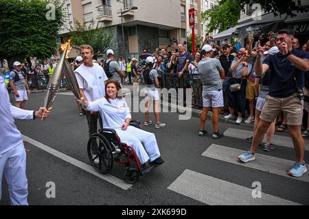 Die libanesische Fotojournalistin Christina Assi trägt die olympische Fackel, um Journalisten zu ehren, die am 21. Juli im französischen Vincennes in der Nähe von Paris verletzt und getötet wurden. 2024. Christina Assi von der Agence France-Presse oder AFP gehörte zu sechs Journalisten, die am 13. Oktober 2023 von israelischen Bomben getroffen wurden, während sie über den Südlibanon berichteten, bei dem Angriff wurde der Fotograf Issam Abdallah von Reuters getötet. Der AFP-Videograf Dylan Collins, der ebenfalls bei demselben Angriff verwundet wurde, schiebt Assis Rollstuhl. Foto: Ammar Abd Rabbo/ABACAPRESS. KOM Stockfoto