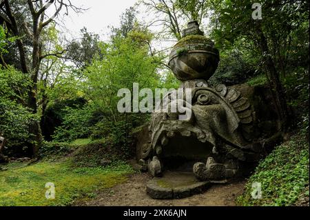 Antike Steinskulptur eines monströsen Gesichts, das den Mythos von Proteus-Glaucus im Heiligen Hain von Bomarzo darstellt. Die Statue, umgeben von üppigem Grün Stockfoto