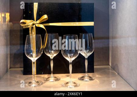 Glasflöten und schwarze Geschenkbox mit goldenem Band auf der Ladenfront. Festliches Silvesterset. Stockfoto