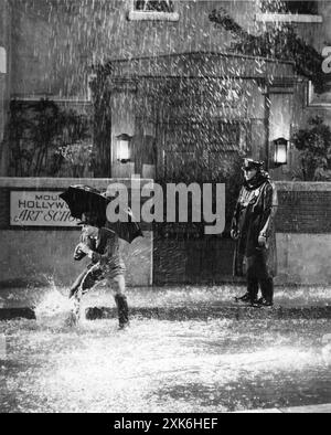 Der amerikanische Tänzer, Choreograf und Schauspieler GENE KELLY spielt die Titelnummer in SINGIN' IN THE RAIN 1952 Regisseur STANLEY DONEN Story von BETTY COMDEN und ADOLPH GREEN Musik und Texte von NACIO HERB BROWN und ARTHUR FREED Costume Design WALTER PLUNKETT Produzent ARTHUR FREED Metro Goldwyn Mayer Stockfoto