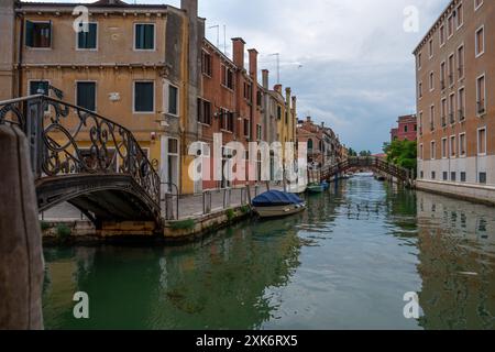 Venedig, Italien - 4. Juni 2024: Ruhiger venezianischer Kanal mit rustikalen Gebäuden und Booten. Stockfoto