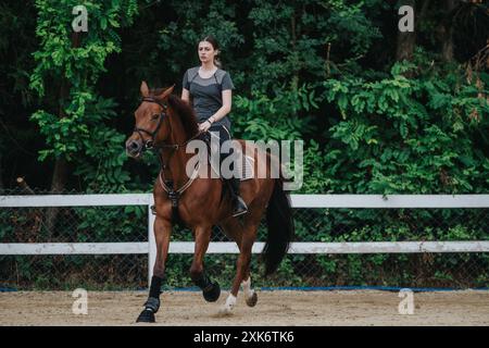 Ein junges Mädchen, das auf einer Ranch auf einem Pferd reitet und sich selbstbewusst und komponiert fühlt Stockfoto