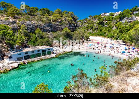 Badebucht mit kristallklarem Wasser, Sandstrand und Bootshäuser in der Bucht von Cala Pi Stockfoto