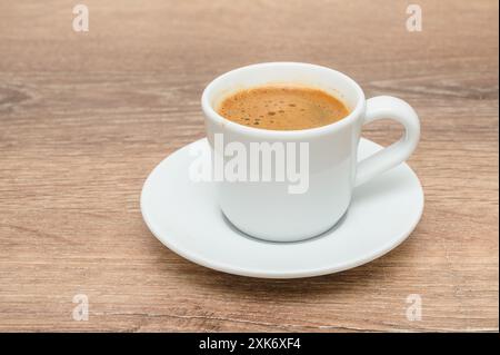 Eine Kaffeetasse wird elegant auf einer Untertasse auf einem Holztisch platziert Stockfoto