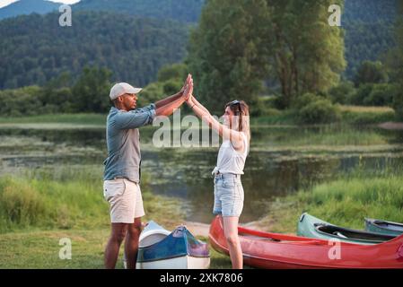 Glückliches Paar, das im Sommer eine Kanufahrt auf dem See genießt und sich inmitten der wunderschönen grünen Natur entspannt. Konzepte für Kanufahrten. Stockfoto