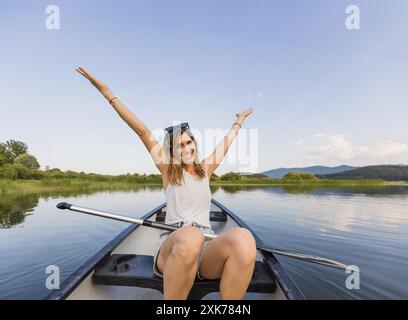 Fröhlich lächelnde Frau, die an einem schönen, ruhigen, sonnigen Sommertag auf einem See Kanu fährt, Nahaufnahme. Urlaubs- und Freizeitkonzepte. Stockfoto