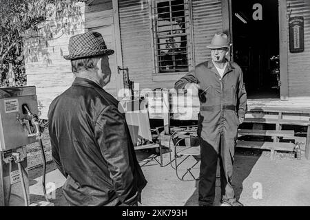 Mazedonien, Arkansas, USA – 27. Juni 2024: Horizontale Aufnahme von zwei alten Freunden, die vor einem alten Landhaus zu Besuch sind. Stockfoto