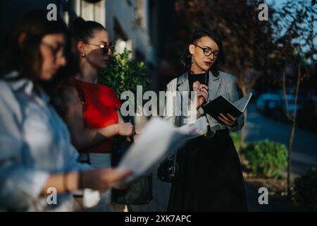 Professionelle Geschäftsfrauen halten ein Treffen im Freien ab, diskutieren Dokumente und machen Notizen Stockfoto