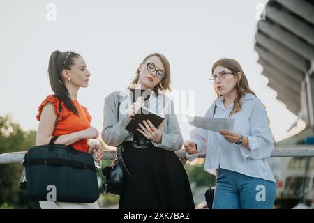 Gruppe von Geschäftsfrauen, die sich im Freien mit Dokumenten und Notizbüchern unterhalten Stockfoto