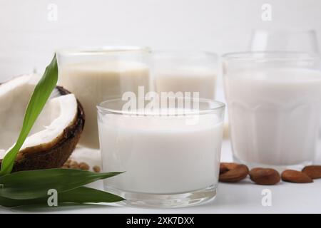 Verschiedene Arten veganer Milch und Zutaten auf weißem Tisch, Nahaufnahme Stockfoto