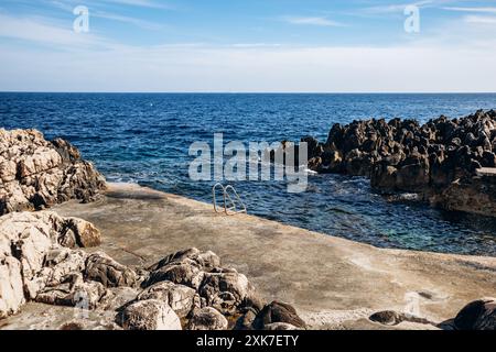 Felsiger Strand mit Geländern ins Wasser auf der Halbinsel Saint Jean Cap Ferrat bei Sonnenuntergang Stockfoto