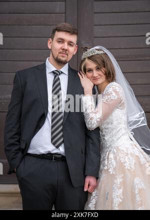 Porträt eines jungen, modernen Paares. Die Braut und der Bräutigam aus der Nähe. Brauner Hintergrund der Fensterläden. Hochzeit, Liebe, neue Familie Stockfoto