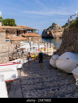 Touristen schlendern durch die schönen alten Straßen des kleinen Küstendorfes Deia auf Mallorca, Spanien. Traditionelle Häuser auf den Hügeln, W Stockfoto