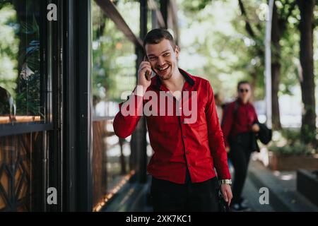 Lächelnder Geschäftsmann telefoniert, während er draußen mit einem Kollegen im Hintergrund läuft Stockfoto