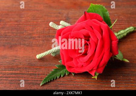 Eine stilvolle rote Boutonniere auf Holztisch, Nahaufnahme. Leerzeichen für Text Stockfoto