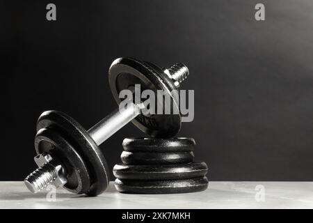 Barbell und Tellerstapel auf hellem Tisch vor dunklem Hintergrund. Leerzeichen für Text Stockfoto