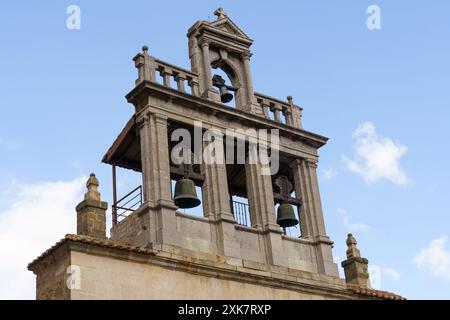 Ein Blick aus der Nähe auf den Glockenturm der Kathedrale Santa Maria de Astorga, mit den komplizierten Details und zwei großen, verwitterten Glocken. Stockfoto