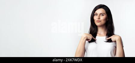 Frau, die in weißem T-Shirt auf sich zeigt Stockfoto