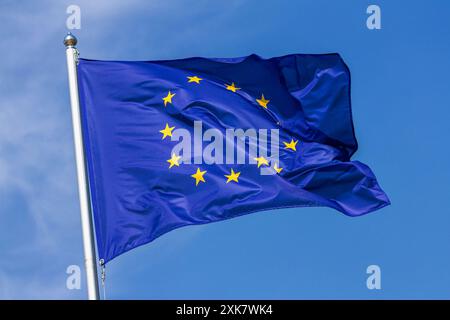Die Flagge der Europäischen Union winkt im Wind am Fahnenmast gegen den Himmel mit Wolken an sonnigen Tagen, Nahaufnahme Stockfoto
